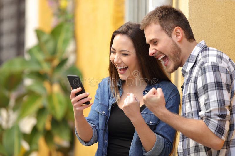 Couples enthousiastes trouvant des offres en ligne au téléphone dans la rue