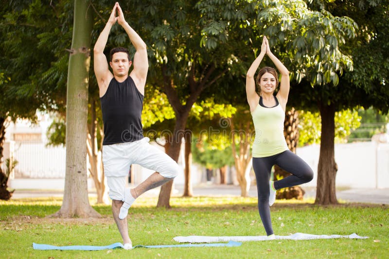 Couples faisant la pose de yoga d'arbre image libre de droits Couples faisant la pose de yoga d'arbre image libre de droits