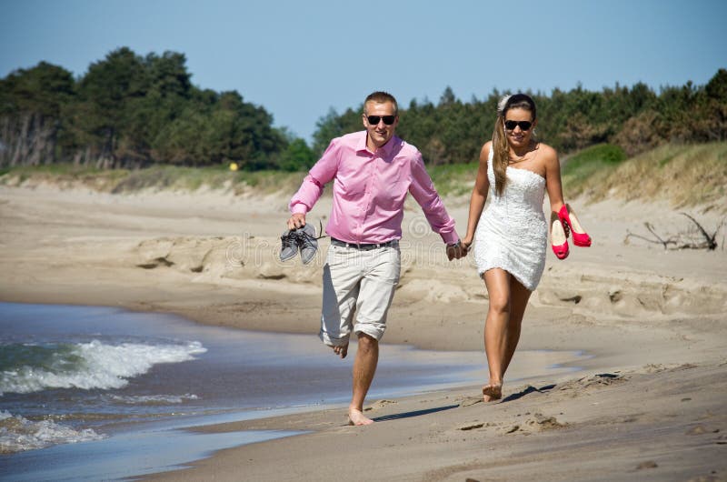 Couples fonctionnant sur la plage photos stock Couples fonctionnant sur la plage photos stock