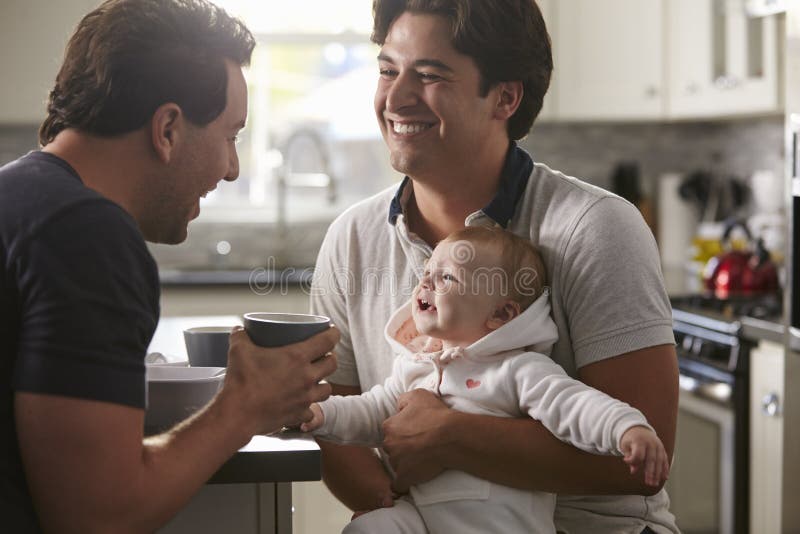 Couples gais masculins tenant le bébé dans leur cuisine