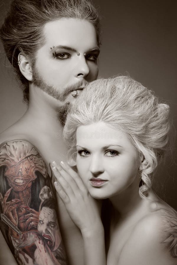Duotone portrait of pierced tattooed man and woman with old-fashioned make-up and hairstyle. Duotone portrait of pierced tattooed man and woman with old-fashioned make-up and hairstyle