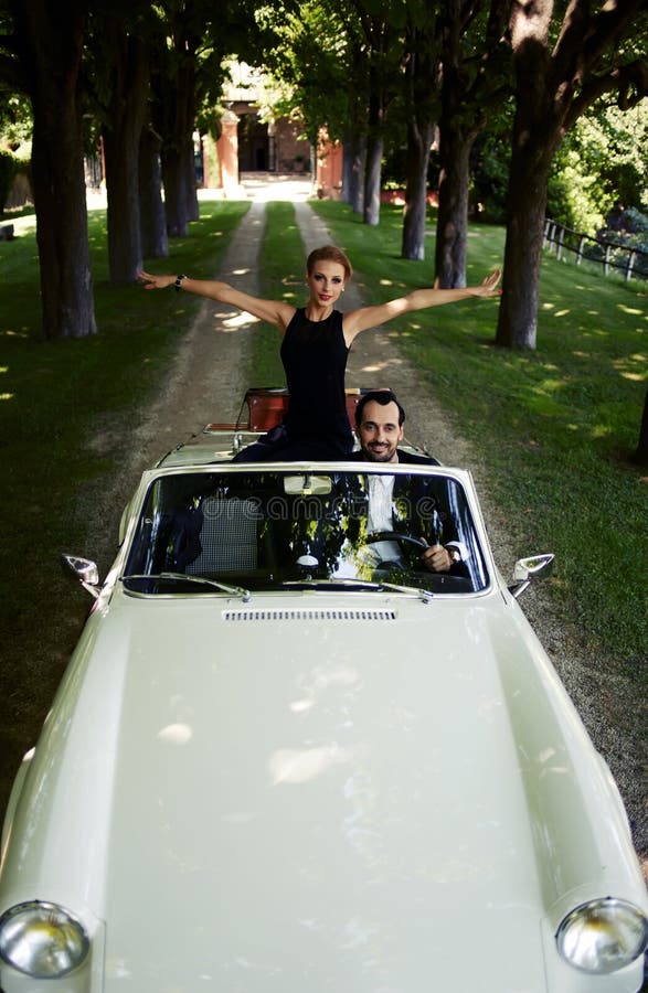Couples heureux appréciant un tour sur leur voiture convertible de luxe pendant l'été photos stock Couples heureux appréciant un tour sur leur voiture convertible de luxe pendant l'été photos stock