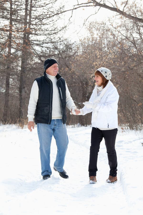 Couples heureux d'aînés marchant en stationnement de l'hiver photographie stock