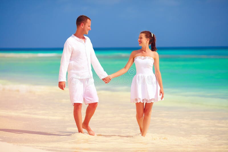 Couples heureux dans l'amour marchant sur la plage tropicale photographie stock libre de droits Couples heureux dans l'amour marchant sur la plage tropicale photographie stock libre de droits
