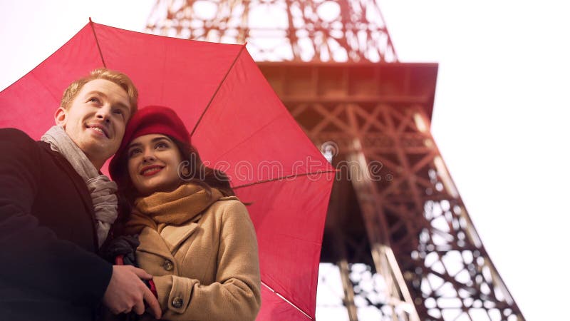Couples heureux dans l'amour se tenant sous le parapluie à Paris, ayant des vacances romantiques image stock Couples heureux dans l'amour se tenant sous le parapluie à Paris, ayant des vacances romantiques image stock