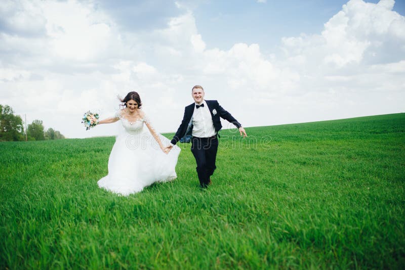 Couples heureux de mariage fonctionnant dans le domaine photographie stock libre de droits Couples heureux de mariage fonctionnant dans le domaine photographie stock libre de droits