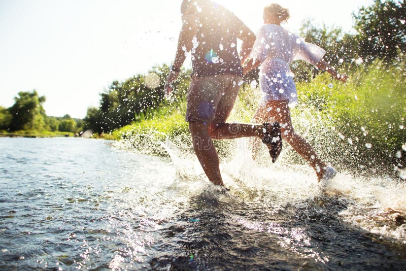 Couples heureux fonctionnant en eau peu profonde images libres de droits Couples heureux fonctionnant en eau peu profonde images libres de droits