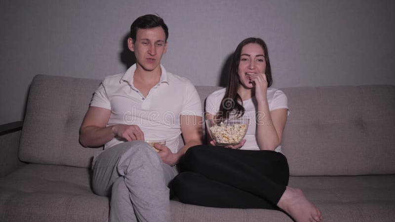 Couples heureux observant un film à la TV se reposant sur un divan à la maison