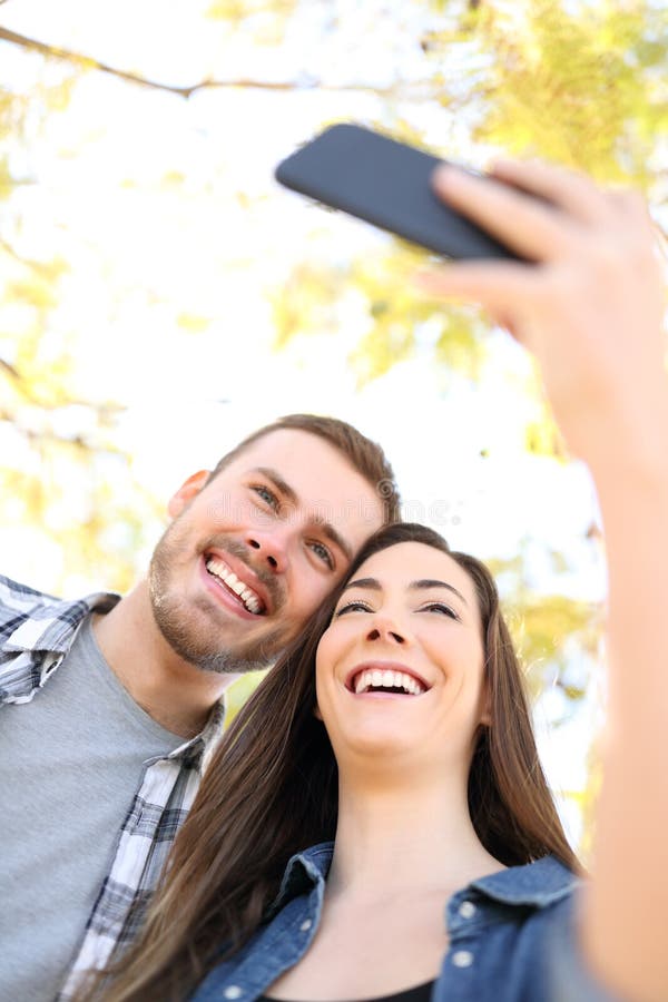 Couples heureux prenant des selfies avec le smartphone image stock Couples heureux prenant des selfies avec le smartphone image stock
