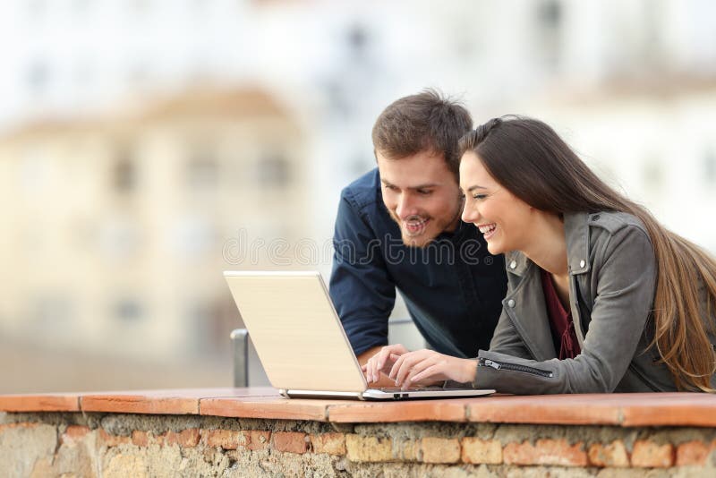 Couples heureux recherchant le contenu en ligne sur un ordinateur portable photo stock Couples heureux recherchant le contenu en ligne sur un ordinateur portable photo stock