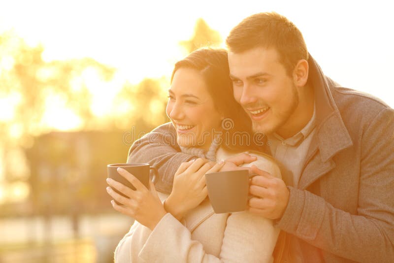 Couples heureux regardant loin en hiver le coucher du soleil photo libre de droits Couples heureux regardant loin en hiver le coucher du soleil photo libre de droits