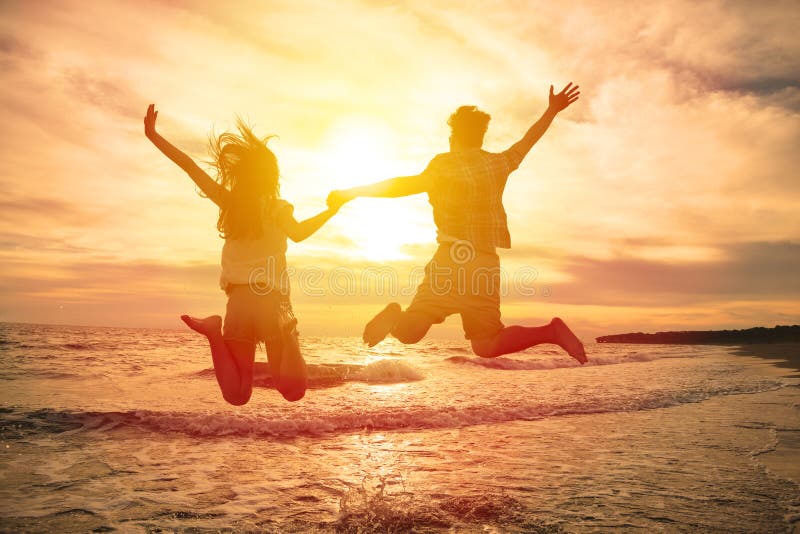 Couples heureux sautant sur la plage photos libres de droits