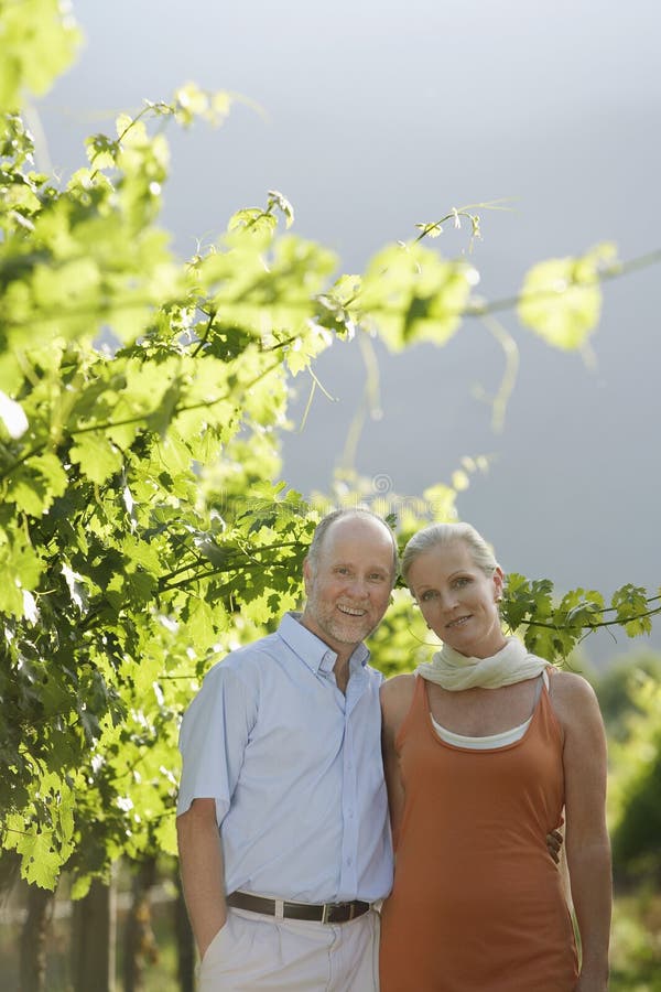 Couples heureux se tenant dans le vignoble images stock Couples heureux se tenant dans le vignoble images stock