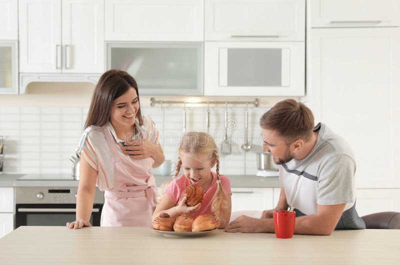 Couples heureux traitant leur fille avec fraîchement le petit pain cuit au four par four photo stock Couples heureux traitant leur fille avec fraîchement le petit pain cuit au four par four photo stock