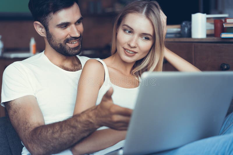 Couples heureux utilisant un ordinateur portable sur le sofa
