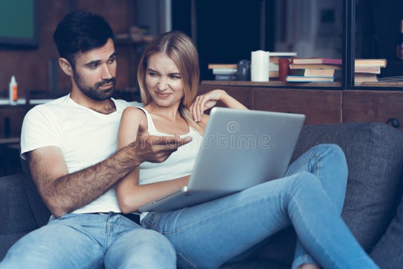 Couples heureux utilisant un ordinateur portable sur le sofa images stock