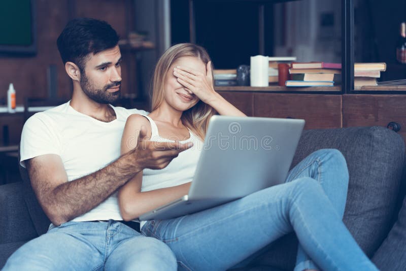 Couples heureux utilisant un ordinateur portable sur le sofa photographie stock libre de droits