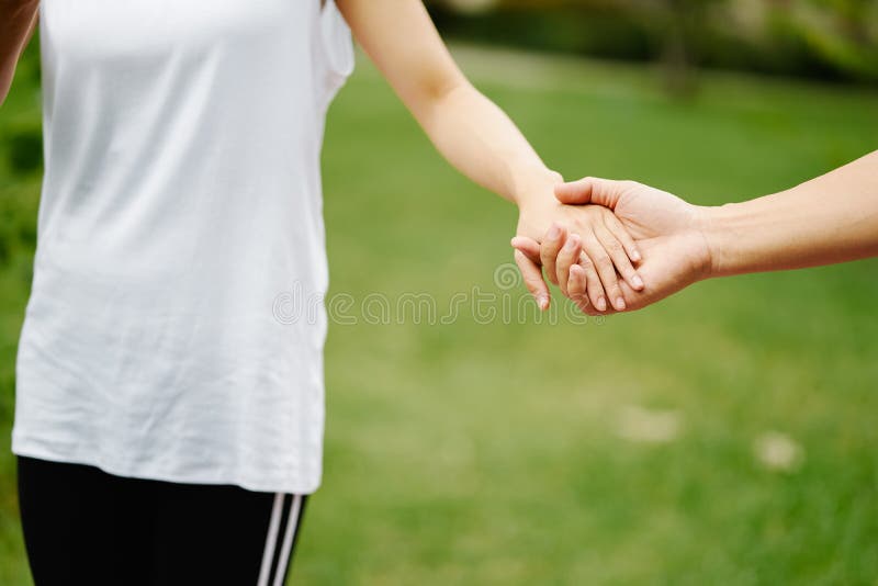 Couples holding hands in front of green grass stock photo Couples holding hands in front of green grass stock photo