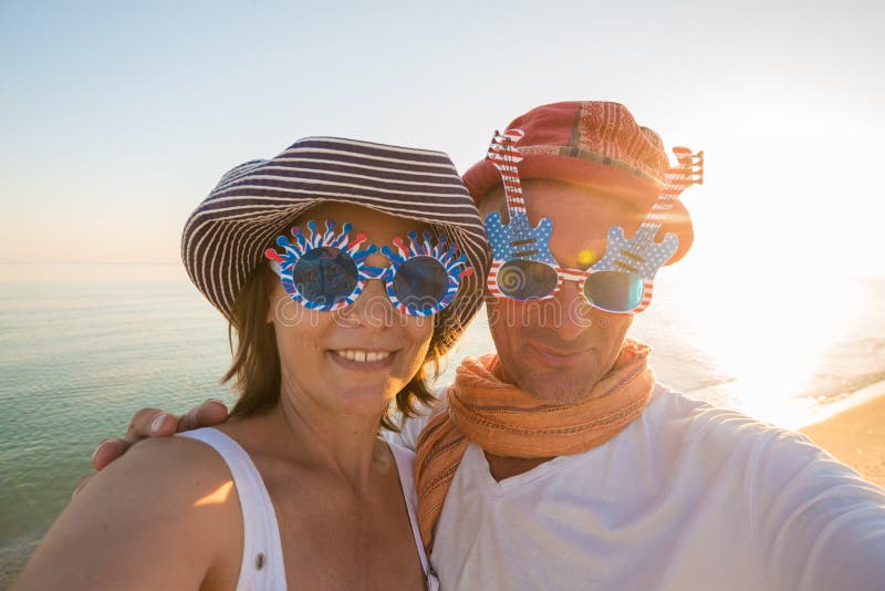 Couples joyeux des voyageurs, dans des lunettes de soleil drôles, prenant le selfie photo stock Couples joyeux des voyageurs, dans des lunettes de soleil drôles, prenant le selfie photo stock