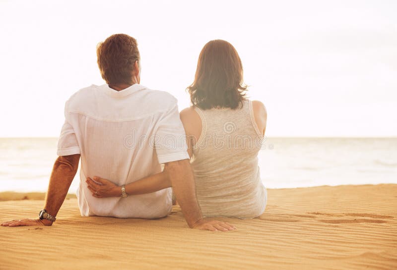 Couples mûrs appréciant le coucher du soleil sur la plage image stock Couples mûrs appréciant le coucher du soleil sur la plage image stock