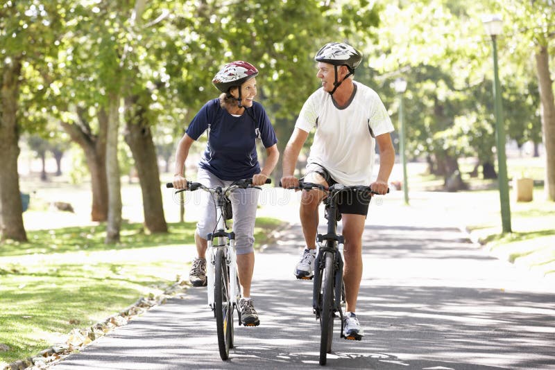 Couples mûrs faisant un cycle par le parc photo libre de droits