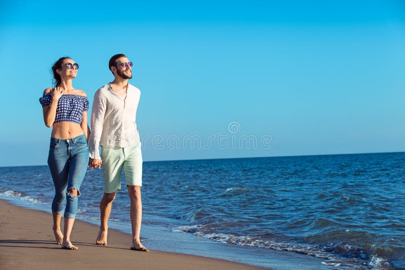Couples marchant par Heron Jeunes couples interraciaux heureux marchant sur la plage images libres de droits Couples marchant par Heron Jeunes couples interraciaux heureux marchant sur la plage images libres de droits