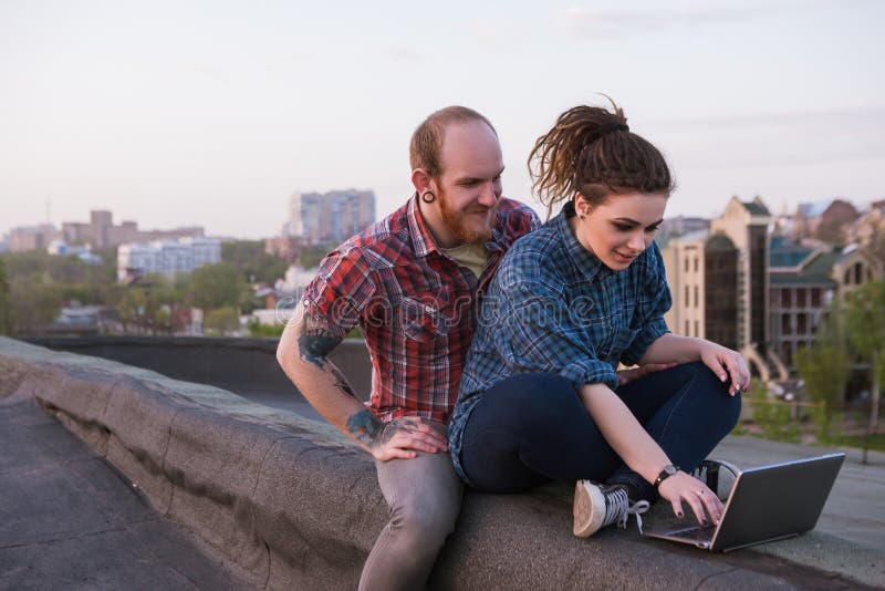 Couples modernes de la jeunesse de hippie sur le toit images libres de droits Couples modernes de la jeunesse de hippie sur le toit images libres de droits