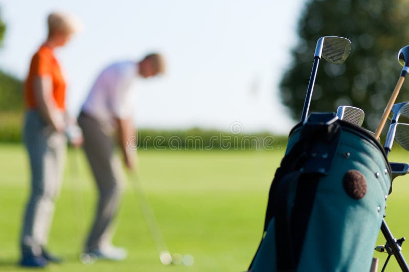 Couples mûrs jouant au golf (orientation sur le sac) photo stock Couples mûrs jouant au golf (orientation sur le sac) photo stock