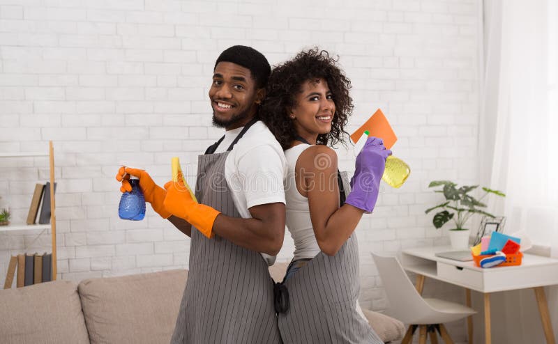 Couples noirs heureux tenant des détergents pendant le nettoyage à la maison image libre de droits Couples noirs heureux tenant des détergents pendant le nettoyage à la maison image libre de droits
