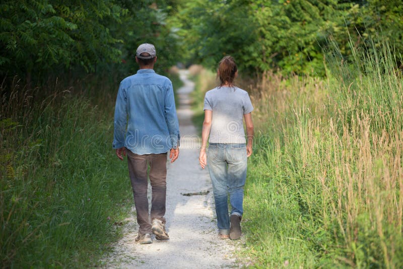 Couples non identifiés de femme d'homme de personnes marchant loin l'arrière d'itinéraire aménagé pour amateurs de la nature