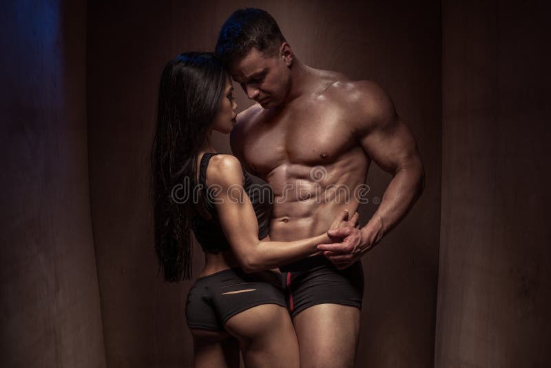 Couples romantiques de bodybuilding contre le mur en bois image libre de droits Couples romantiques de bodybuilding contre le mur en bois image libre de droits