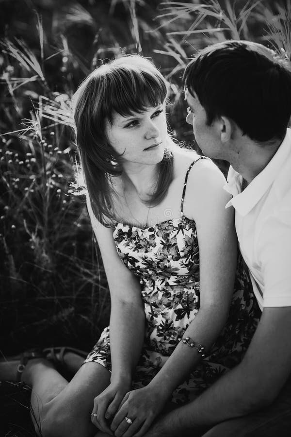 Couples romantiques de photographie blanche noire se tenant et embrassant sur le pré d'été de fond photo stock Couples romantiques de photographie blanche noire se tenant et embrassant sur le pré d'été de fond photo stock