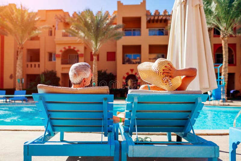 Couples sup?rieurs d?tendant par la piscine se trouvant sur des chaises longues Les gens appr?ciant des vacances d'?t? photographie stock libre de droits Couples sup?rieurs d?tendant par la piscine se trouvant sur des chaises longues Les gens appr?ciant des vacances d'?t? photographie stock libre de droits