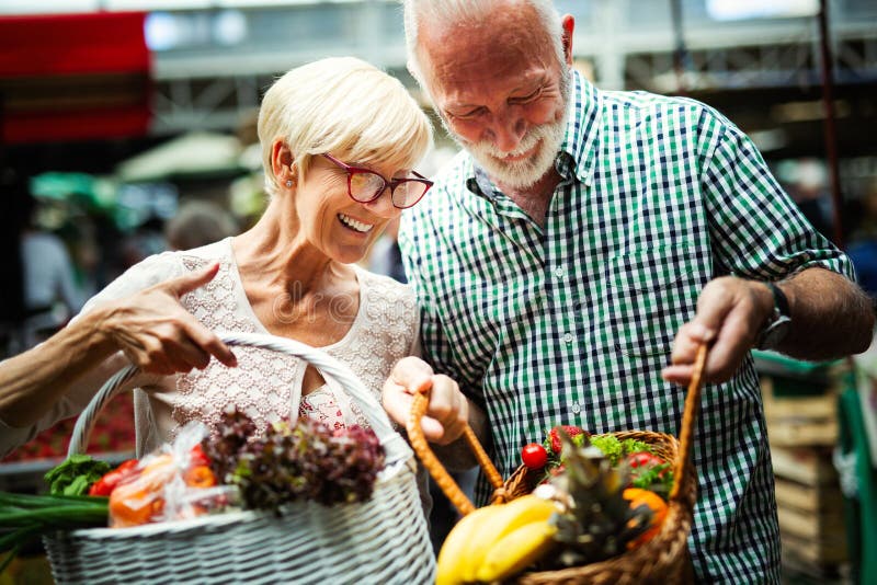 Couples supérieurs de famille choisissant de bio fruits et légumes de nourriture sur le marché pendant des achats hebdomadaires image libre de droits Couples supérieurs de famille choisissant de bio fruits et légumes de nourriture sur le marché pendant des achats hebdomadaires image libre de droits