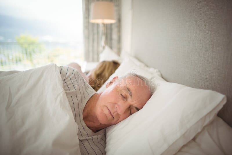 Couples supérieurs dormant sur le lit image libre de droits Couples supérieurs dormant sur le lit image libre de droits