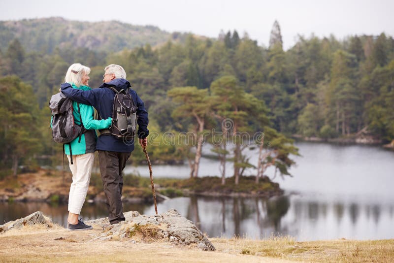 Couples supérieurs embrassant et admirant une vue des lacs regardant l'un l'autre, de retour vue images libres de droits Couples supérieurs embrassant et admirant une vue des lacs regardant l'un l'autre, de retour vue images libres de droits