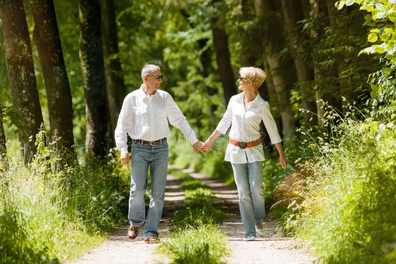 Mature or senior couple running, deeply in love having a walk holding each other tight in late spring or early summer. Mature or senior couple running, deeply in love having a walk holding each other tight in late spring or early summer