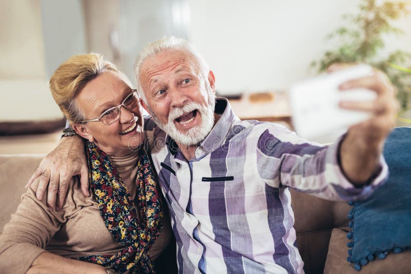 Couples supérieurs heureux se reposant ensemble sur un sofa dans leur salon photographie stock Couples supérieurs heureux se reposant ensemble sur un sofa dans leur salon photographie stock