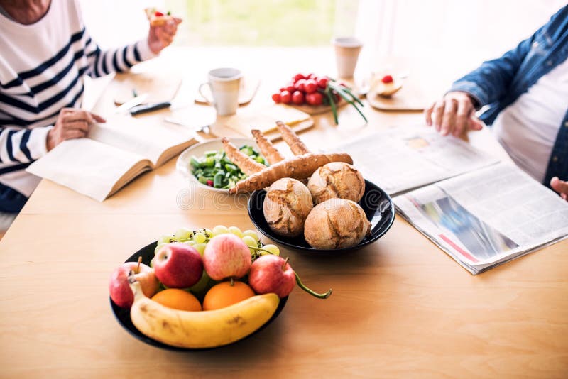 Couples supérieurs mangeant le petit déjeuner à la maison image libre de droits Couples supérieurs mangeant le petit déjeuner à la maison image libre de droits