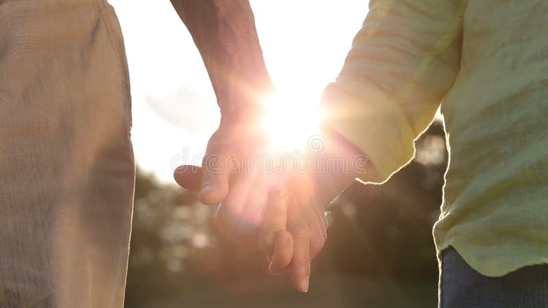 Couples supérieurs romantiques tenant des mains au coucher du soleil