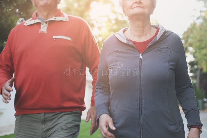 Couplez dans l'habillement de sports ayant l'exercice dans le parc de ville C photos stock Couplez dans l'habillement de sports ayant l'exercice dans le parc de ville C photos stock
