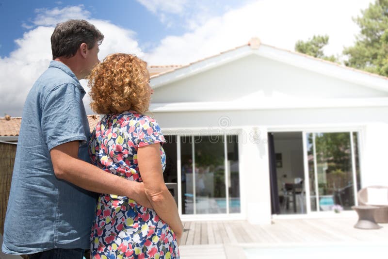 Couplez l'embrassement devant la nouvelle maison moderne, vue arrière image stock Couplez l'embrassement devant la nouvelle maison moderne, vue arrière image stock