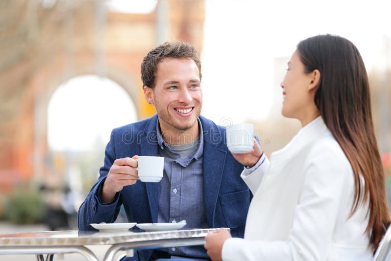 Couple dating drinking coffee at sidewalk cafe outdoors on date. Young beautiful professionals talking enjoying espresso laughing having in Barcelona, Spain near Arc de Triomf on Passeig de Sant Joan. Couple dating drinking coffee at sidewalk cafe outdoors on date. Young beautiful professionals talking enjoying espresso laughing having in Barcelona, Spain near Arc de Triomf on Passeig de Sant Joan.