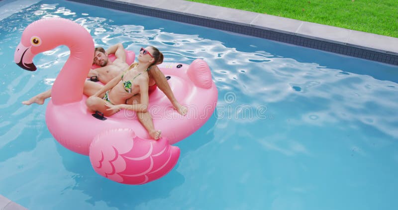 Couplez le sommeil ensemble sur le tube gonflable dans la piscine 4k banque de vidéos