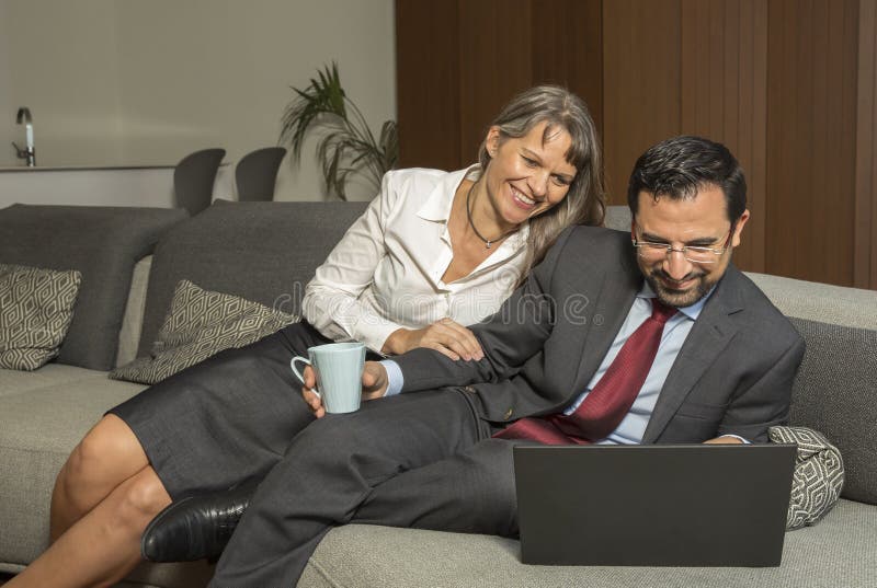 Couplez à la maison dans le formalware avec le fonctionnement de l'homme et l'observation de femme photos stock Couplez à la maison dans le formalware avec le fonctionnement de l'homme et l'observation de femme photos stock