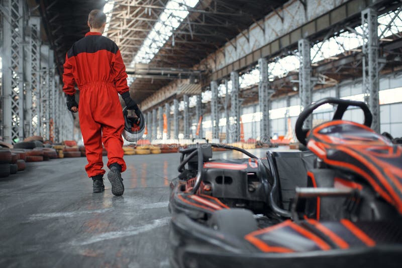 Coureur avec casque près de la voiture de karting, vue arrière photo libre de droits Coureur avec casque près de la voiture de karting, vue arrière photo libre de droits
