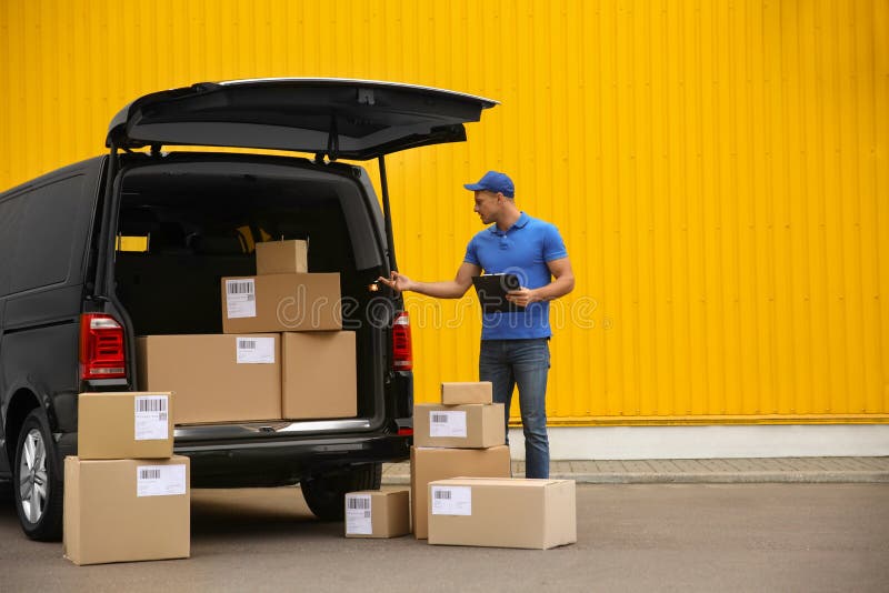 Courier with clipboard and parcels near delivery van outdoors stock images