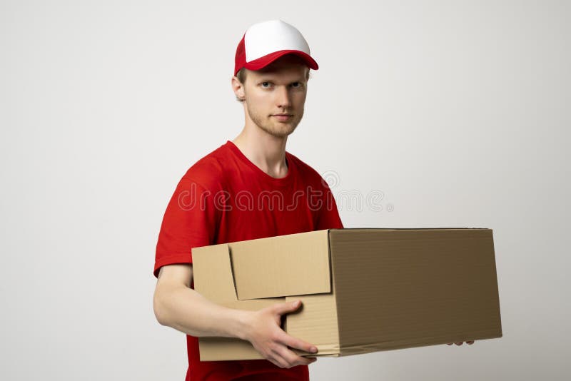 Courier man in a red uniform holding a cardboard box. Parcels Delivery Service Concept. stock photos