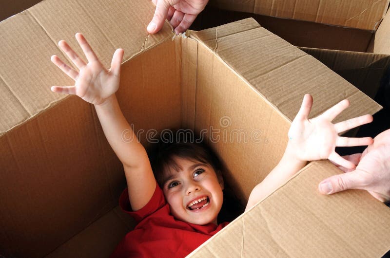 Couro cru feliz da menina dentro de uma caixa de cartão grande que move-se em um hou novo imagem de stock royalty free