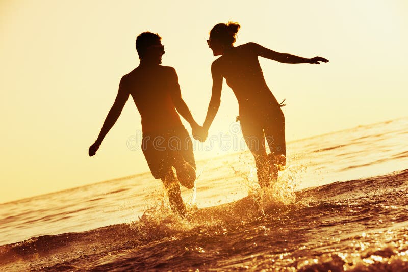 Course heureuse de mer de coucher du soleil de couples photo stock Course heureuse de mer de coucher du soleil de couples photo stock